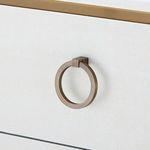 Round brass drawer pull attached to white textured linen drawer front