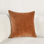 Pillow styled on white sofa showcasing size and rich burnt orange color