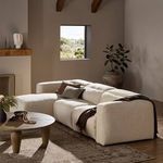 Styled sectional in neutral-toned living room with pillows, throw, wooden coffee table, and decorative plants