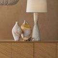 Bowl displayed on wood cabinet next to two decorative vases and a textured white table lamp