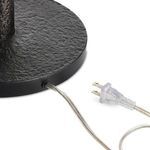 Close-up showing power cord exiting textured round black metal lamp base