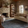 Rug shown in rustic living room setting beneath beige sofa and armchair