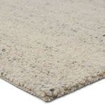 Close-up showing chunky wool yarn and textured loops in cream, gray, and black flecks