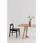 Dining table in minimalist setting with black chair and decorative vase with flowers on table