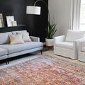 Layla Spice Marine Rug styled in living room with gray sofa, white armchair, black accent wall, and arc floor lamp