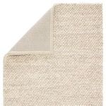 Rug corner flipped to reveal gray fabric backing with sewn edge trim