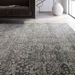 Rug viewed from low angle with dark sofa on top, highlighting textured markup of floral design