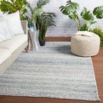 Rug styled in a patio setting with wicker sofa, cushions, plants, and wooden deck flooring
