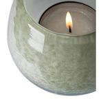 Close-up showing lit candle inside the greenish glass lantern vase