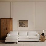 Full view of Hutton sectional in styled room with lamp, wooden armoire, wall art, and neutral tones