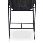Close-up of thick upholstered cushion resting inside black woven arm chair frame
