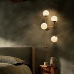 Armstrong 4 R Sconce illuminated on wall above wooden nightstand with cup and pitcher in ambient lighting