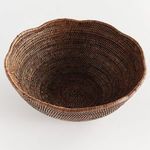 Overhead view focused on woven spiral detail at the center of the scalloped-edge rattan bowl