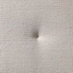 Close-up of cream fabric cushion texture with visible tuft button