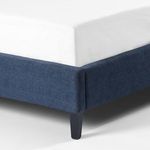 Close-up detail of indigo fabric wrapped around corner of footboard and sleek black leg