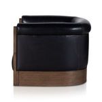 Side close-up capturing smooth leather upholstery and curved wood armrest detail