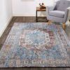 Armant rug styled in a bright room beneath a gray armchair, showing full rug area and flooring context