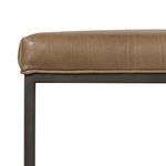 Detailed side view showing leather overhanging frame with cushion piping edge