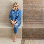 Person sitting barefoot next to two rugs with contrasting woven patterns and colors
