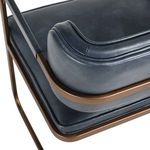 Close-up of backrest contours and welted leather stitching accented by bronze frame