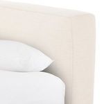 Close-up side view of cream linen slipcovered bed skirt and frame