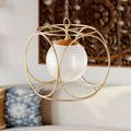 Pendant light hanging near a wooden carved wall art, with blue and yellow cushions on sofa below