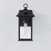 Front view of outdoor wall sconce mounted on a light gray wall with clear glass and visible bulb.