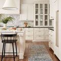 Runner-sized rug in a bright white kitchen with black chair and white cabinetry on hardwood floor