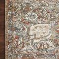 Detailed corner of the rug on a wood floor showing the faded traditional design and fine weaving.
