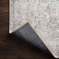Folded corner of Loren Silver / Slate rug flipped to show dark woven backing and beige stitched edge
