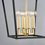 Close-up of four clear globe bulbs with aged brass candle-style sockets inside black frame