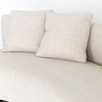 Close-up on a pair of square cushions with piped edges resting on a curved sofa back