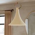 Close-up side view of Radcliff pendant showing curved brass hardware and chain with beige curtain and mirror background