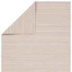 Top view of rug with one corner folded to show reverse side of cream and tan diamond pattern