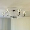 Full chandelier installed on flat ceiling in a minimalist room with light walls and empty outlets