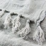 Close-up of natural linen throw showing knotted fringe detail and woven texture