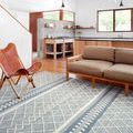 Sawyer Teal Rug styled under sofa and chair in modern living room with wooden floor and large windows