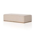 Close-up of ottoman edge emphasizing smooth fabric surface and wooden plinth base