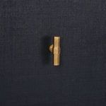 Close-up of geometric gold leaf hardware against navy raffia door texture