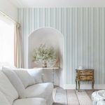 Wallpaper with delicate pastel blue and white watercolour vertical stripes in a bright, coastal style living room