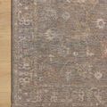 Corner of the Louisa Stone Multi Rug lying flat on light wood flooring highlighting intricate border details.