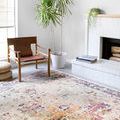 Clara Ivory/Charcoal Rug in a bright room next to leather chair, potted plant, and white brick fireplace