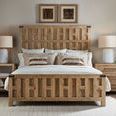 Bedroom setup with bed centered between nightstand and dresser, bed made with layered neutral pillows and bedding