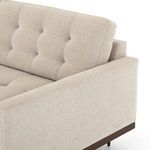 Close-up side angle showing fabric wrapped armrest and tapered wooden leg of mid-century sectional