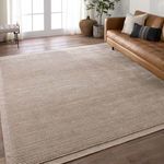 Light brown rug styling in a bright living room with tan leather sofa, plants, and wood floor