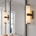 Brenham Brass Wall Sconce mounted in bathroom setting with mirror, flowers, and soft warm light