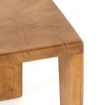 Close-up of stool’s smooth rounded top corner and visible wood grain in warm teak finish