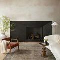 Adrian rug styled in a living room by dark stone fireplace with chair and modern sofa