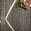 Close-up showing woven wool and cotton texture and tonal braided patterns with decorative shelf items