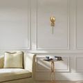Ambient shot of sconce on wall above beige sofa and wooden side table in softly lit elegant room